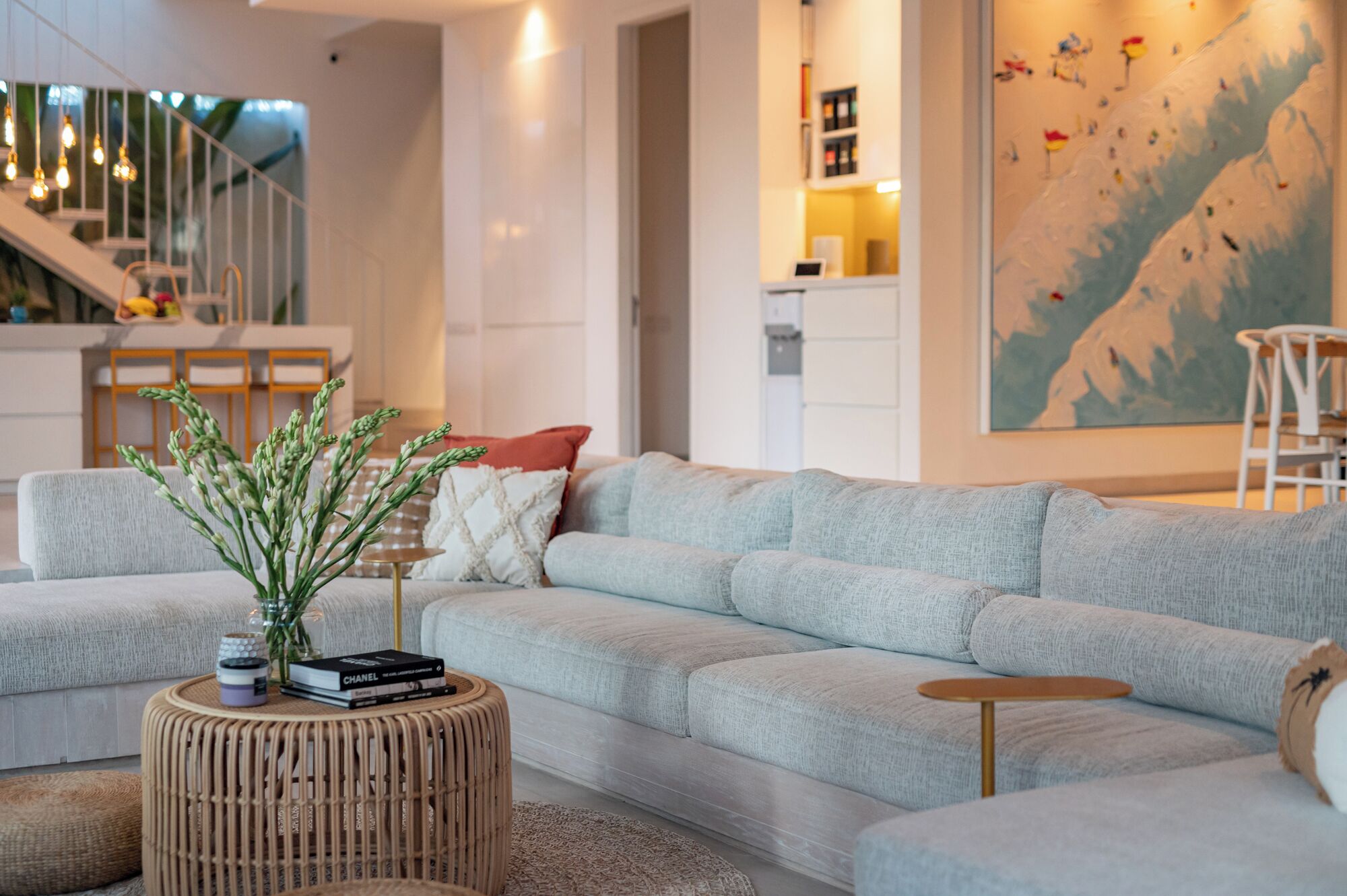 A modern living room with a grey sectional sofa, a round wooden coffee table, and a large abstract painting on the wall.