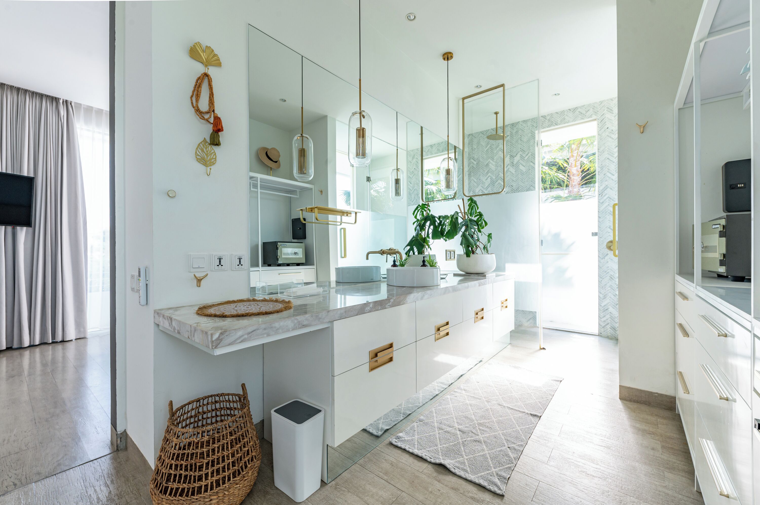 Un baño moderno con un espejo grande, muebles blancos y una planta.