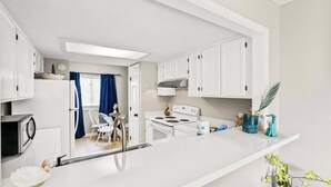 A modern kitchen with white cabinets, a stove, and a sink.
