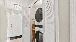 A laundry room with a washing machine and dryer, a door, and a ceiling light fixture.