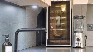 A modern kitchen with a built-in refrigerator, a stainless steel blender, and a soap dispenser on the counter.