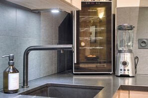 A modern kitchen with a built-in refrigerator, a stainless steel blender, and a soap dispenser on the counter.