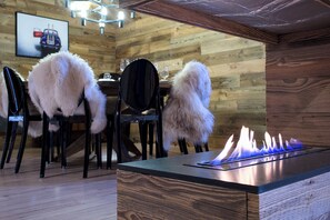 A wooden interior with a dining area, chairs, and a table with a built-in gas stove.