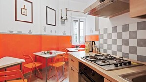 Uma cozinha com fogão a gás, pia e cadeiras laranja ao redor de uma mesa.
