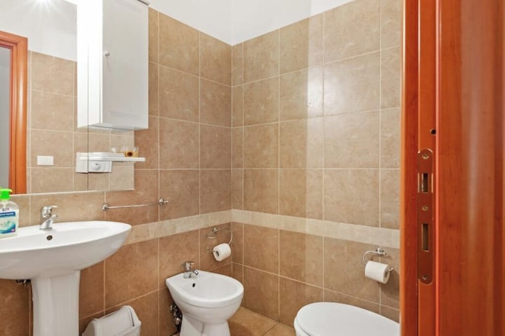 A bathroom with a sink, bidet, toilet, and a mirror.