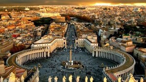 Visão em ângulo amplo da Praça de São Pedro, na Cidade do Vaticano, destacando a emblemática Basílica de São Pedro, com sua cúpula central e colunatas ao redor.