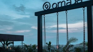 Une porte battante ornée du logo « QomaYa » à l’entrée d’un complexe hôtelier.