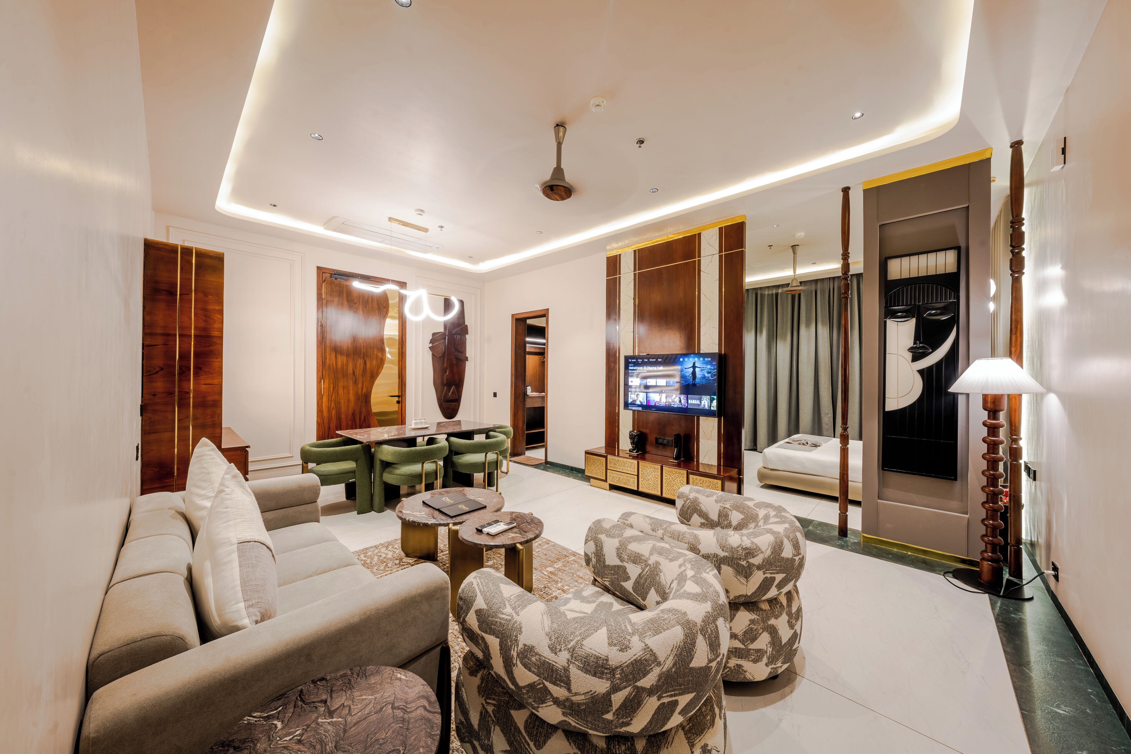 A modern living room with a sofa, armchairs, a coffee table, a TV, and a dining area.