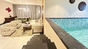 Une chambre d’hôtel moderne dotée d’un espace de vie, d’une piscine et d’un escalier menant à la piscine.