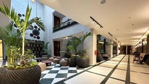 Un hall d’entrée spacieux, doté d’un sol à carreaux, de plusieurs espaces aménagés pour s’asseoir et de plantes d’intérieur.