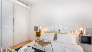 Ein Schlafzimmer mit Bett, Nachttischen, einem Kleiderschrank und einem kleinen Tisch mit Tassen.