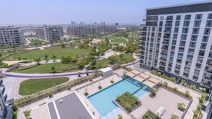 A modern residential complex with a central swimming pool, landscaped gardens, and high-rise buildings in the background. - Chic 1-bed for 4 in Prime Dubai Hills Location (Dubai)