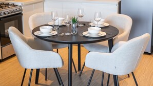 A modern kitchen with a round dining table set for four, surrounded by four chairs. - Chic 1-bed for 4 in Prime Dubai Hills Location (Dubai)