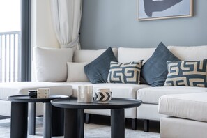 En moderne stue med en hvid sofa, to sorte runde borde og dekorative puder.