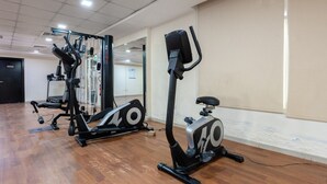 Ein Fitnessstudio mit Laufbändern, Kraftgeräten und einer Spiegelwand.
