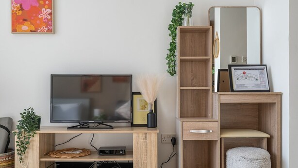 Un meuble en bois pour la télévision, sur lequel est posée une télévision à écran plat, ainsi qu’un certificat encadré et un miroir.