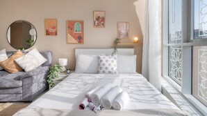 Une chambre d’hôtel avec un lit, un canapé, une table de chevet avec une lampe et des œuvres d’art accrochées au mur.