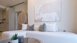 A modern living room with a sofa, cushions, a glass coffee table, a potted plant, and a wall art piece. - Relaxing 3BR in Palm Jumeirah With Beach Views (Dubai)