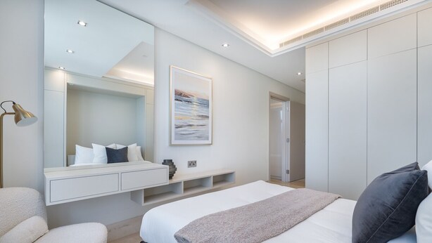 A modern bedroom with a large bed, a bedside table, a mirror, and a wall-mounted artwork. - Relaxing 3BR in Palm Jumeirah With Beach Views (Dubai)