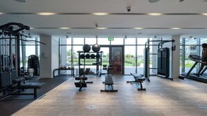 A modern gym with various exercise equipment, large windows, and a clean, spacious layout. - Relaxing 3BR in Palm Jumeirah With Beach Views (Dubai)
