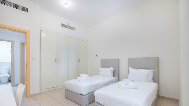 Une chambre d’hôtel avec deux lits simples, une armoire et une petite table.