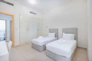 Een hotelkamer met twee eenpersoonsbedden, een kledingkast en een klein tafeltje.