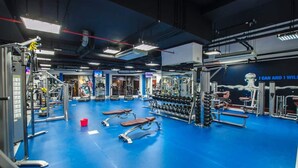 Un gimnasio con diferentes máquinas de ejercicio, bancos y mancuernas.