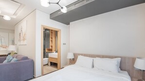 Ein modernes Hotelzimmer mit einem großen Bett, einer Sitzecke, einem Badezimmer und einem Holzschrank.