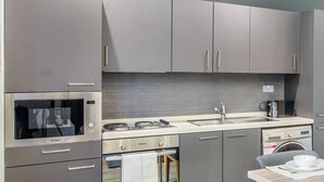Eine moderne Küche mit Edelstahlgeräten, grauen Schränken und einem eingebauten Backofen.
