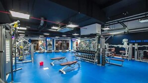 Une salle de sport équipée de divers appareils d’exercice, de bancs et d’haltères.