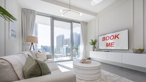 Ein modernes Wohnzimmer mit einer Couch, einem runden Couchtisch und einem an der Wand befestigten Fernseher.