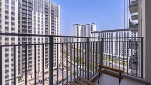 A balcony with a view of high-rise buildings and a busy street below. - Chic 1BR Flat Stunning Views in Dubai Hills (Dubai)