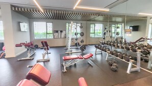 A gym with various exercise equipment, including dumbbells, benches, and weight machines. - Chic 1BR Flat Stunning Views in Dubai Hills (Dubai)