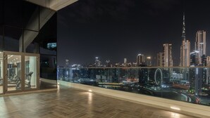 Een moderne hotelkamer met een groot glazen balkon met uitzicht op een stadsbeeld 's nachts.