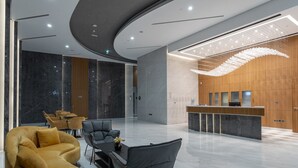 Een moderne lobby met een gebogen plafond, marmeren vloer, een receptiebalie en zithoeken.