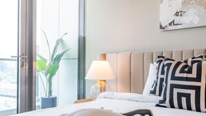Een hotelkamer met een bed, een bedlamp, een potplant en een raam met uitzicht.