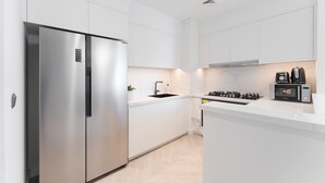 A modern kitchen with white cabinetry, a stainless steel refrigerator, a sink, a stove, and a microwave. - Luxurious 3-bedroom Apartment in Downtown Near Burj Khalifa in Dubai Mall (Dubai)