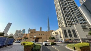 Un paysage urbain avec des immeubles modernes de grande hauteur, un gratte-ciel imposant au centre et un ciel bleu dégagé.