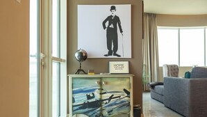 A living room with a sofa, a console table with a globe and a framed picture, and a large window with curtains. - Amazing 4-bedroom Apartment Perfect for Families in Dubai Marina (Dubai)