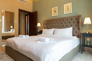 A neatly made bed with white linens and rolled towels, a tufted headboard, and two framed artworks on the wall. - Amazing 4-bedroom Apartment Perfect for Families in Dubai Marina (Dubai)