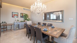 A dining area with a large wooden table, six chairs, a chandelier, and a large mirror on the wall. - Amazing 4-bedroom Apartment Perfect for Families in Dubai Marina (Dubai)