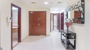 A hallway with a wooden door, a console table with a vase, and a decorative mirror on the wall. - Scenic 2BR Near Beach in Princess Tower Marina (Dubai)