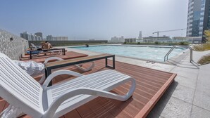 Un espace piscine aménagé sur le toit, avec des chaises longues et une vue sur le panorama urbain.