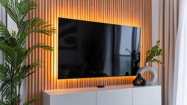 Un meuble de divertissement moderne comprenant un téléviseur à écran plat, un meuble blanc et des vases décoratifs.