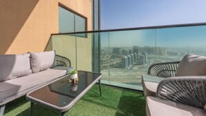 Un balcon doté d’une paroi en verre, d’un canapé, d’une chaise et d’une petite table sur laquelle est posée une plante.