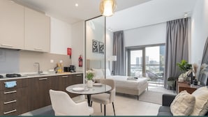 Une chambre d’hôtel moderne dotée d’une kitchenette, d’un coin repas, d’une chambre avec une grande fenêtre et d’un balcon.