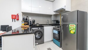Eine kleine Küche mit Waschmaschine, Backofen und Kühlschrank.