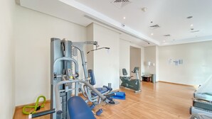 A gym with various exercise equipment, including a weight machine and a bench. - Classy 1-bedroom Apartment in Dubai Marina With City Views (Dubai)