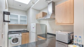 A compact kitchen with a washing machine, microwave, and toaster. - Classy 1-bedroom Apartment in Dubai Marina With City Views (Dubai)