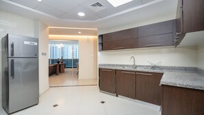 A modern kitchen with stainless steel appliances, dark wooden cabinets, and a granite countertop. - Spacious 3-bedroom With Comfortable Living Area in Dubai Marina (Dubai)